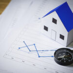 House model and compass on plan background, Real estate concept